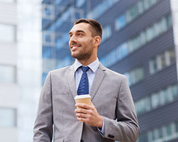 Business person standing and smiling while holding coffee